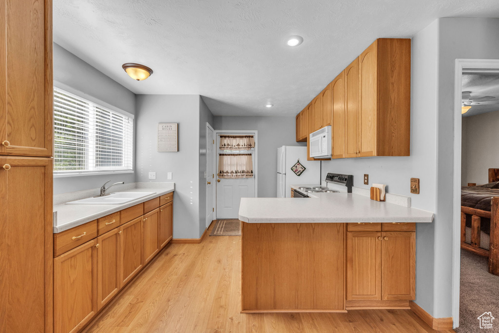 Kitchen featuring white appliances, a sink, a peninsula, light countertops, and recessed lighting