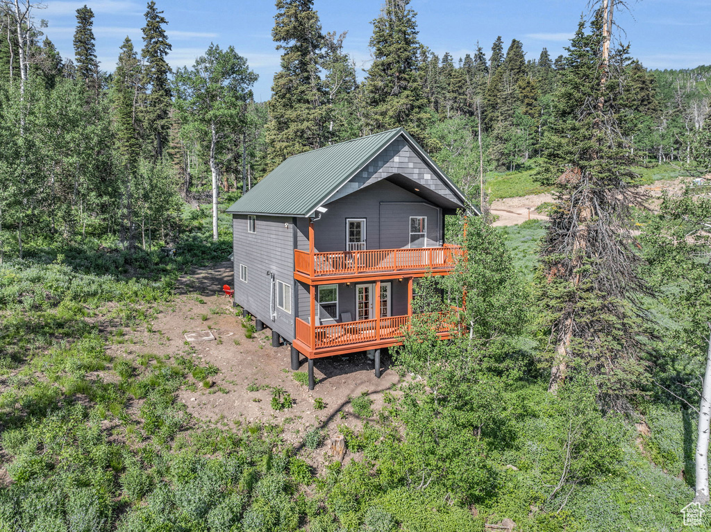 Back of property with a deck, a forest view, and metal roof