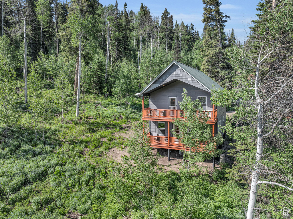 View of side of property with a wooded view and a wooden deck