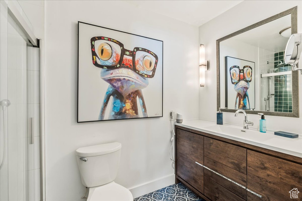 Full bath with toilet, vanity, baseboards, and a shower with door