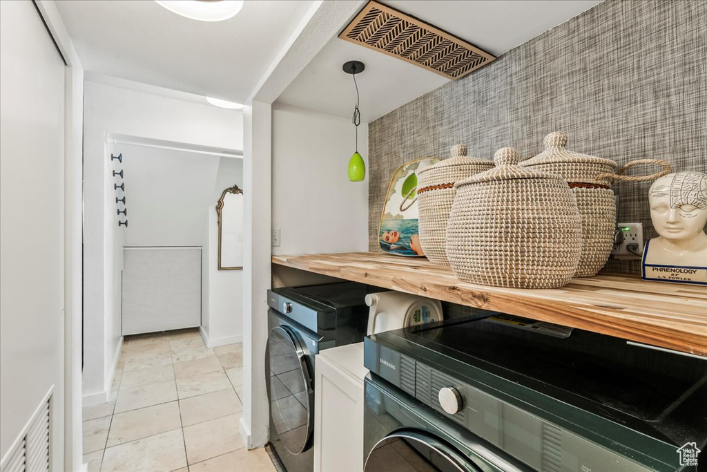 Laundry area with washer and dryer, light tile patterned floors, and baseboards
