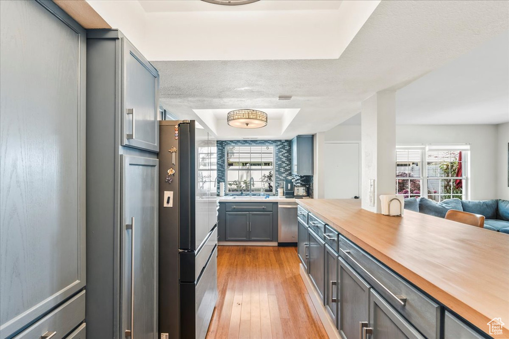 Kitchen featuring wooden counters, a tray ceiling, light wood-style flooring, gray cabinetry, and open floor plan
