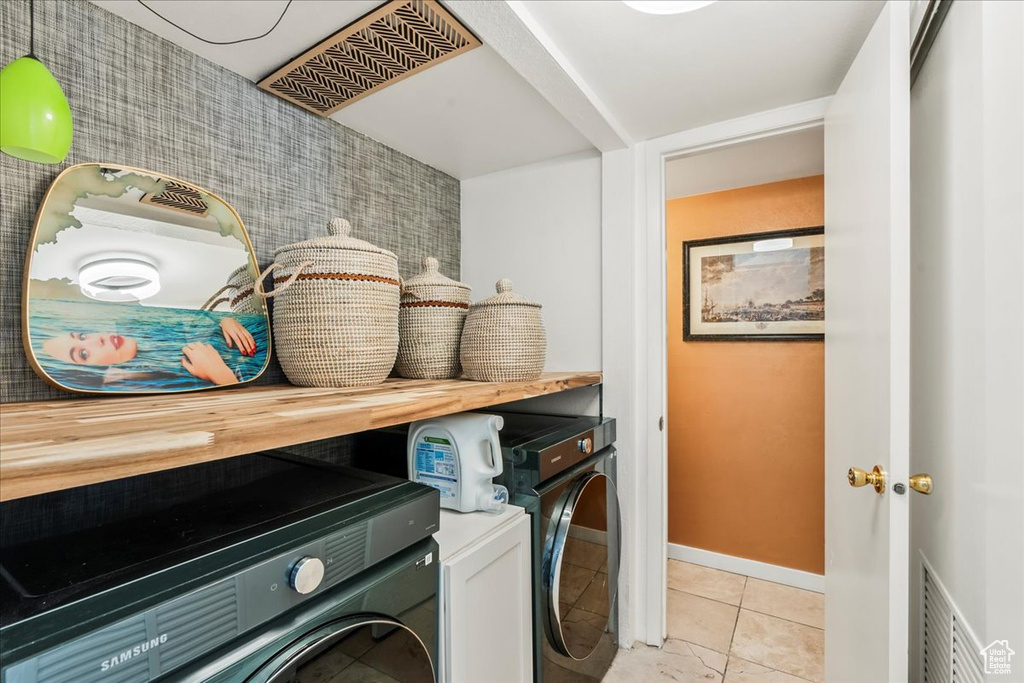 Laundry room with washing machine and dryer, baseboards, and light tile patterned floors