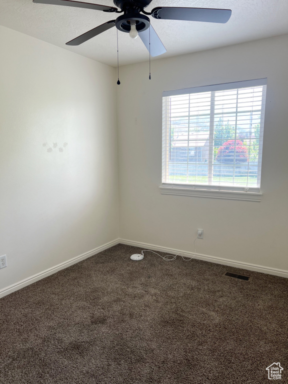 Carpeted spare room with a ceiling fan and baseboards