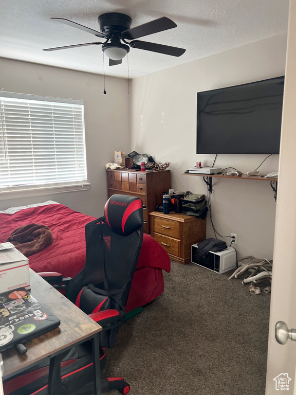 Carpeted bedroom featuring ceiling fan and a textured ceiling