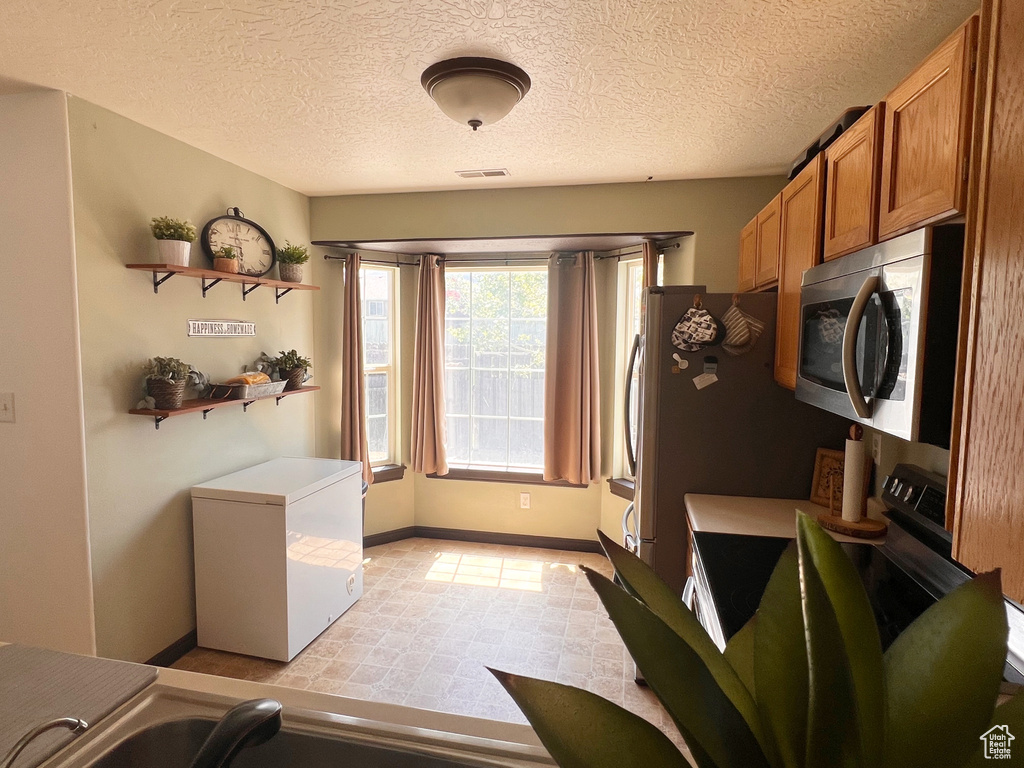 Laundry room with baseboards and a textured ceiling