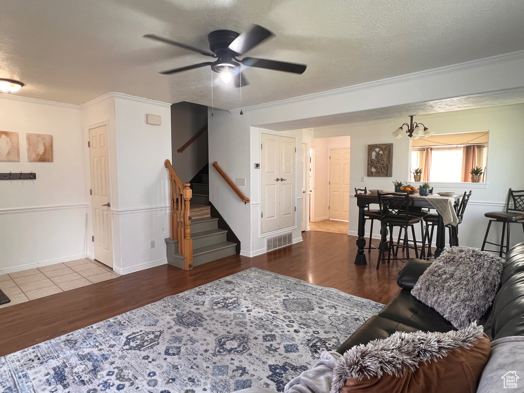Living area with wood finished floors, crown molding, ceiling fan, stairway, and baseboards