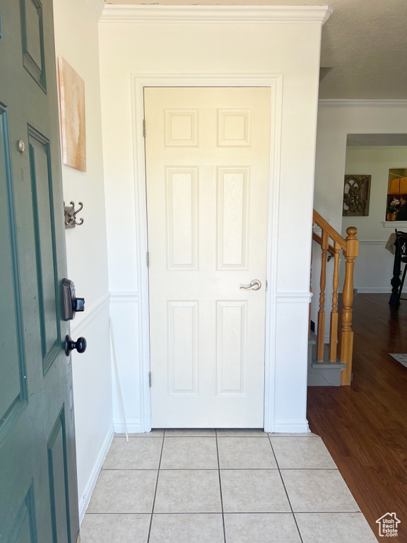 Foyer entrance featuring crown molding, light tile patterned flooring, stairs, and baseboards