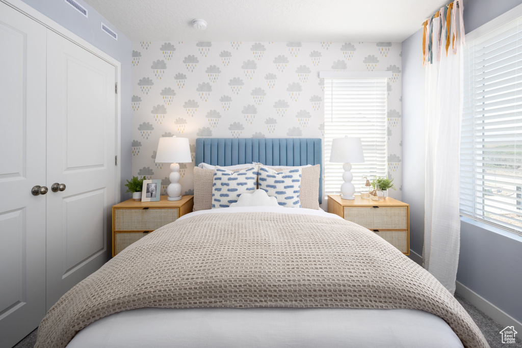 Bedroom featuring wallpapered walls, baseboards, a closet, and carpet