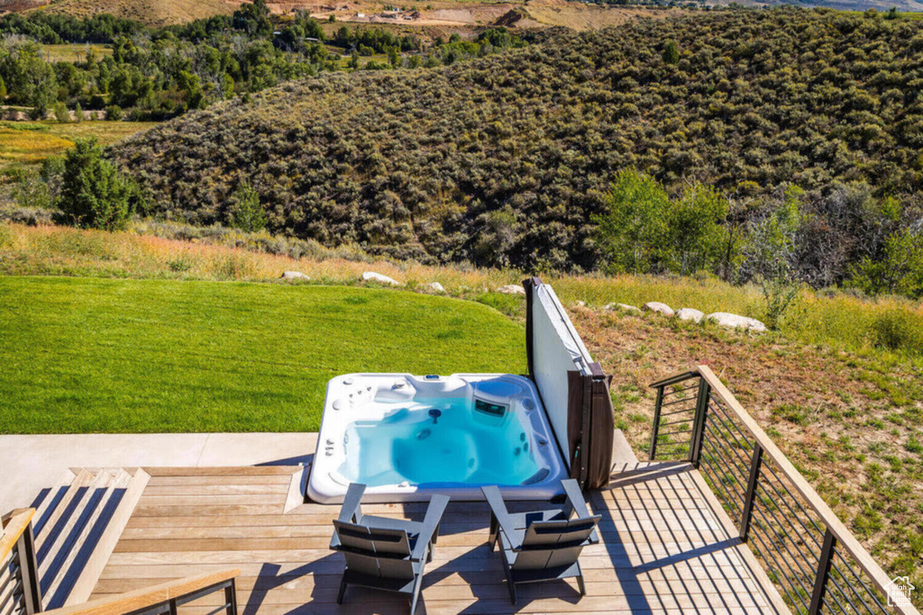 Wooden terrace featuring an outdoor hot tub and a lawn