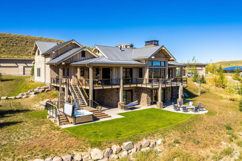 Back of property with a patio, stairs, board and batten siding, an outdoor fire pit, and a deck