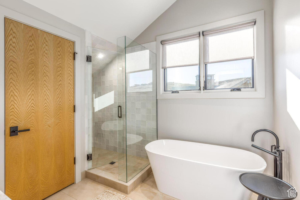 Full bath with a shower stall, a freestanding bath, vaulted ceiling, and tile patterned floors