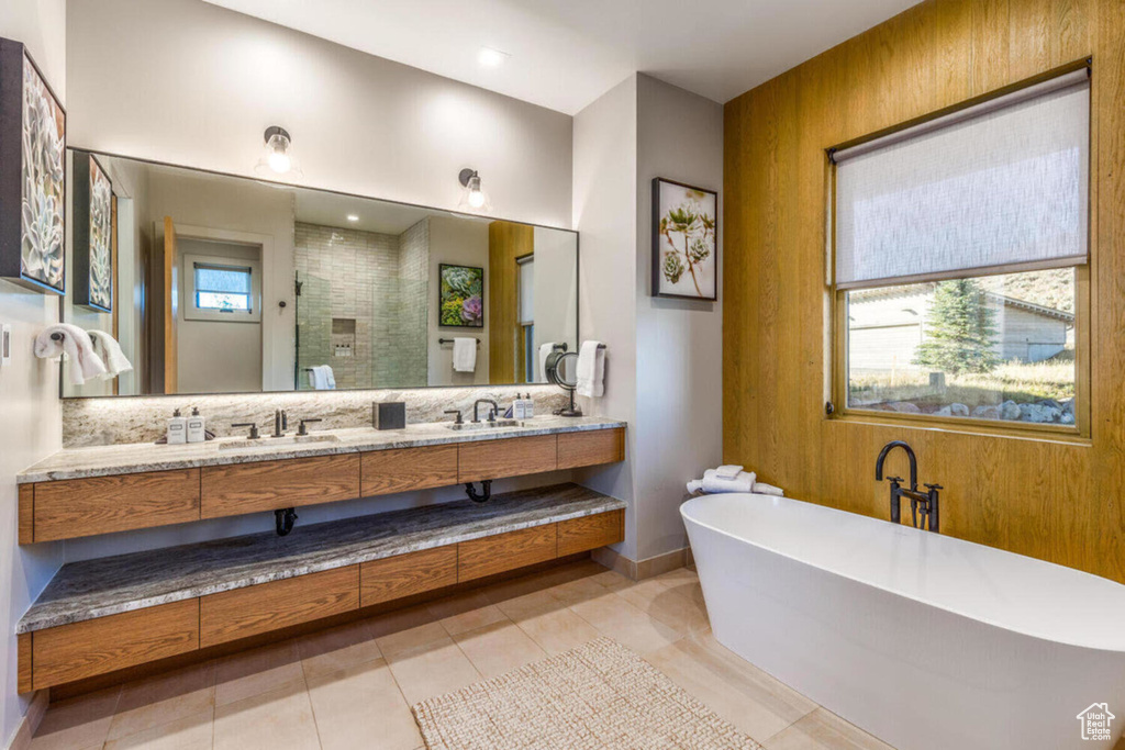 Full bathroom with a shower stall, a freestanding bath, double vanity, tile patterned flooring, and baseboards