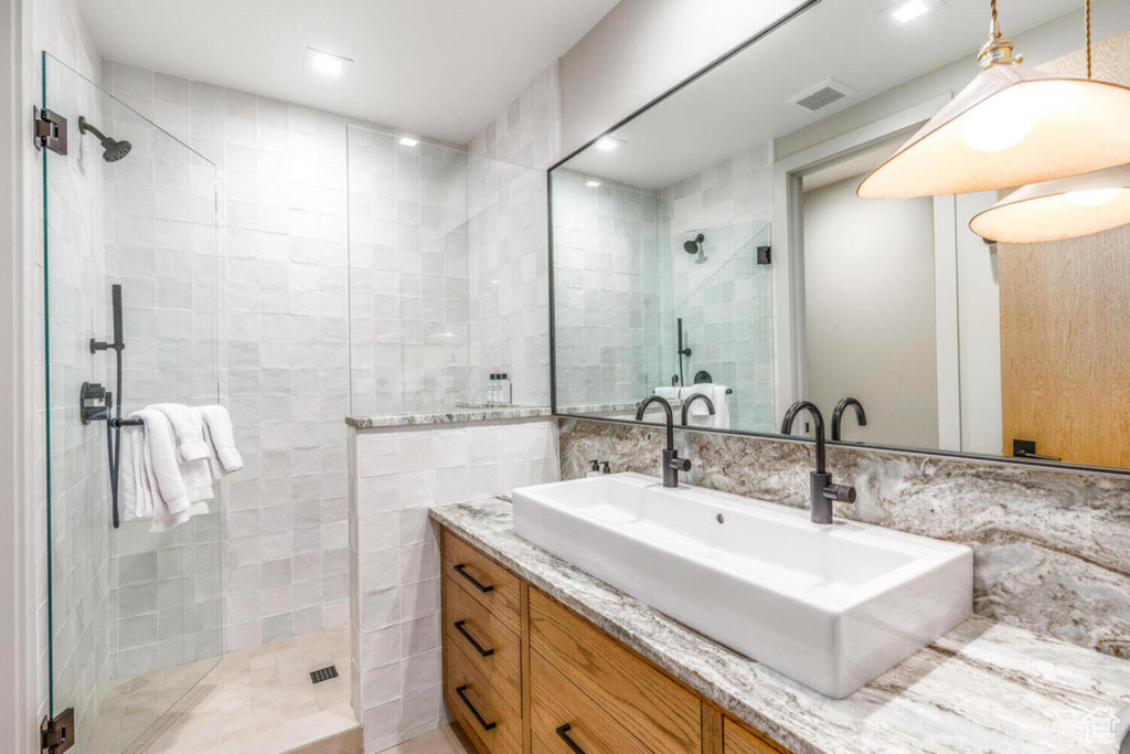 Bathroom featuring tile walls, a shower stall, and vanity