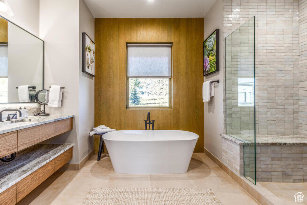 Bathroom featuring a stall shower, healthy amount of natural light, baseboards, a freestanding bath, and wood walls