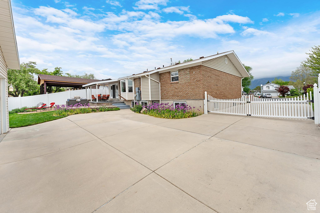 View of side of home with brick siding, a patio area, and fence
