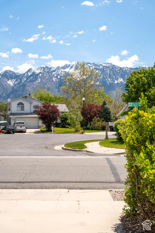 View of asphalt road featuring a mountain view and street lights