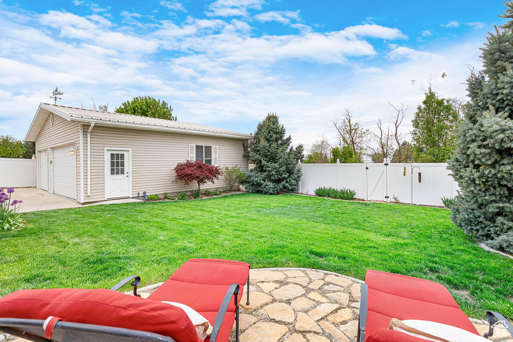 View of yard with a gate, a patio area, and an outdoor structure