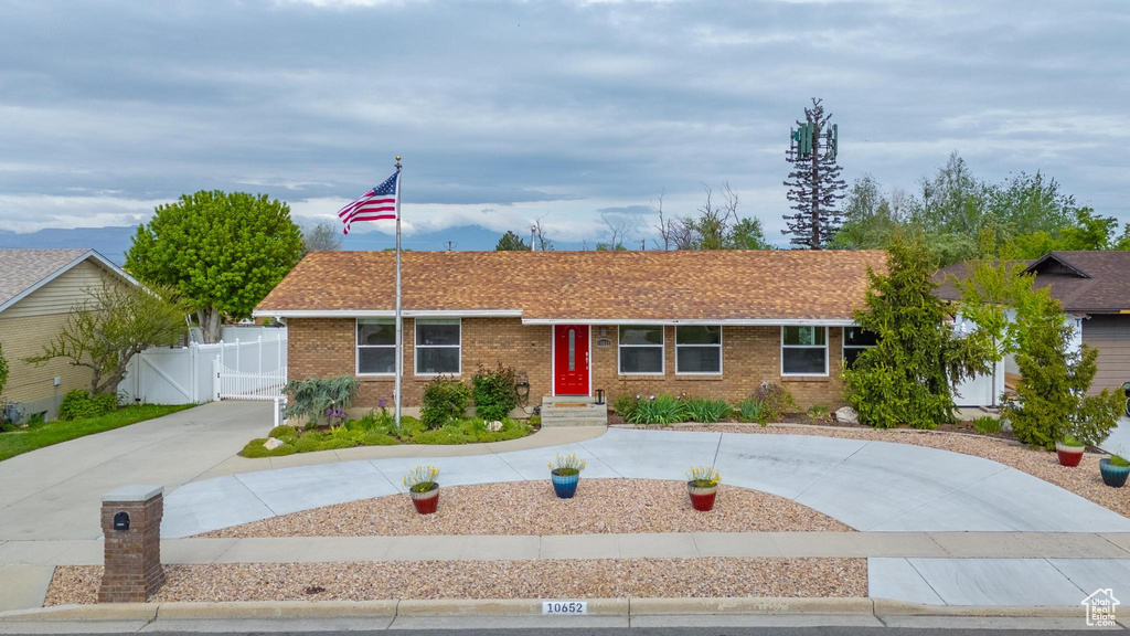 Ranch-style house with a gate, curved driveway, brick siding, and fence