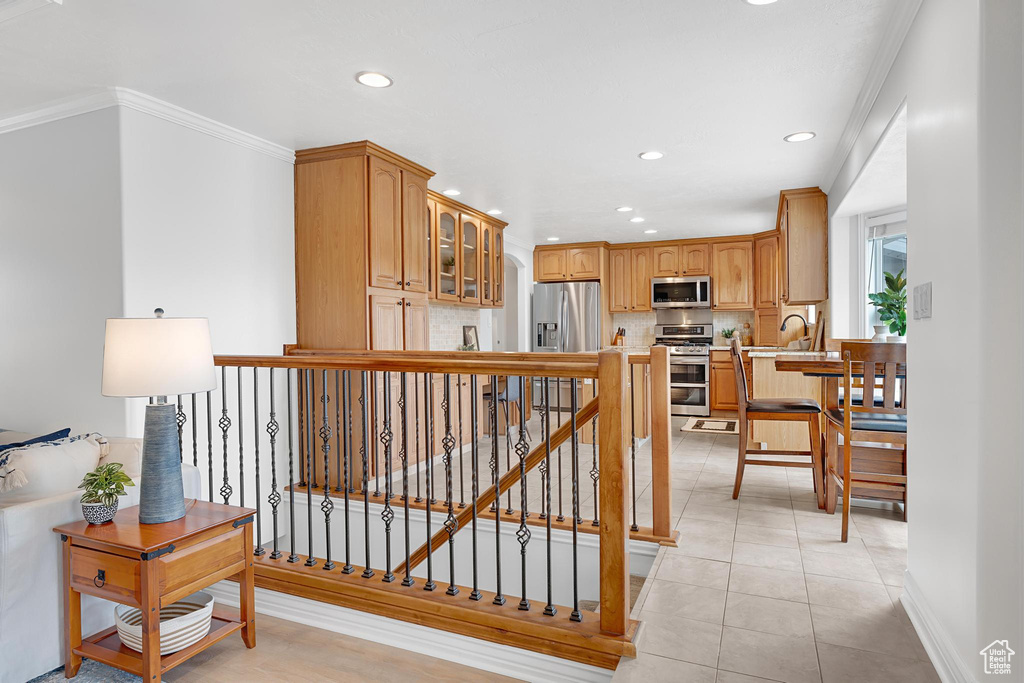 Hall featuring recessed lighting, ornamental molding, light tile patterned floors, a sink, and stairway