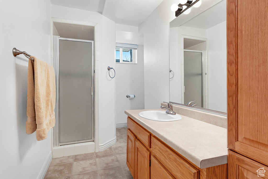 Full bathroom with baseboards, a stall shower, and vanity