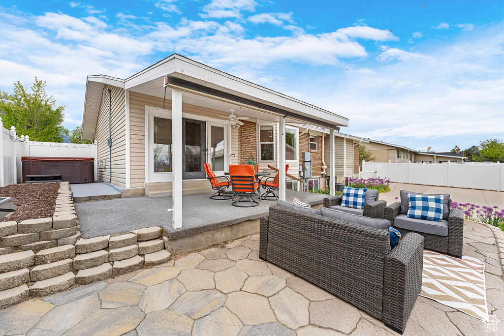 View of patio featuring a fenced backyard, outdoor lounge area, ceiling fan, and a hot tub