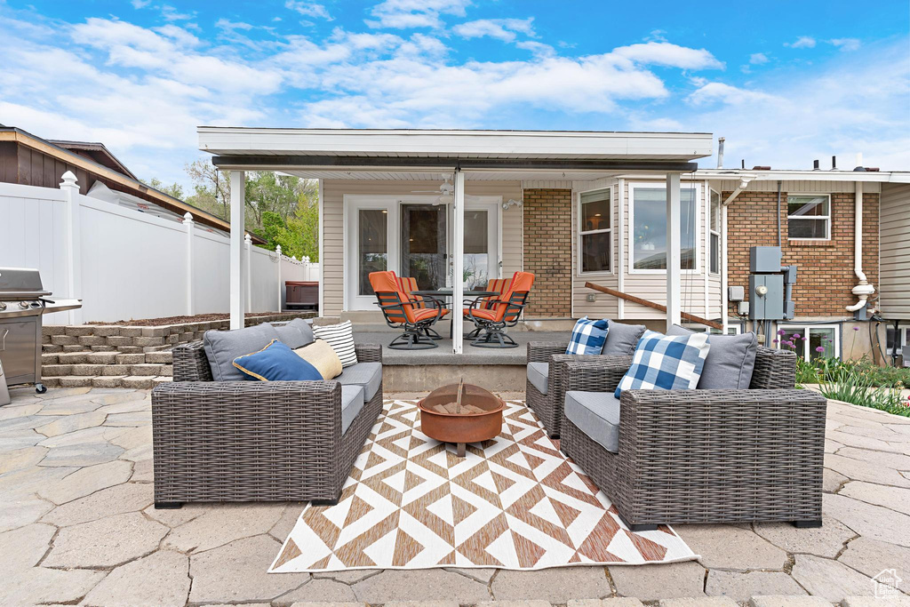 View of patio featuring an outdoor living space with a fire pit, fence, a grill, and outdoor dining space