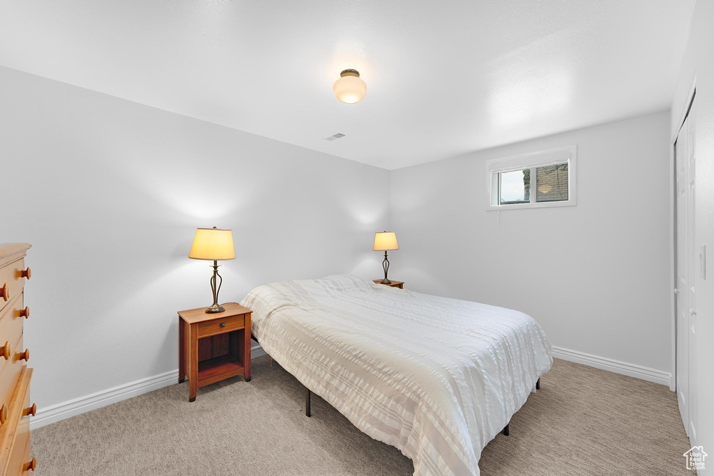 Bedroom featuring light colored carpet, baseboards, and a closet