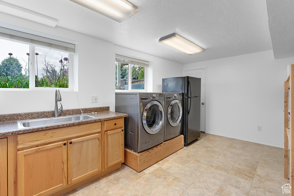 Laundry room with washer and clothes dryer, cabinet space, and a textured ceiling