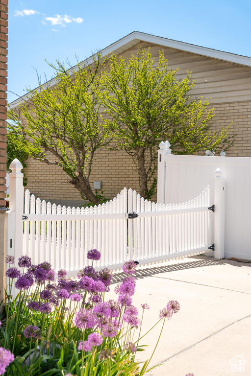 View of side of property with a gate, fence, and brick siding
