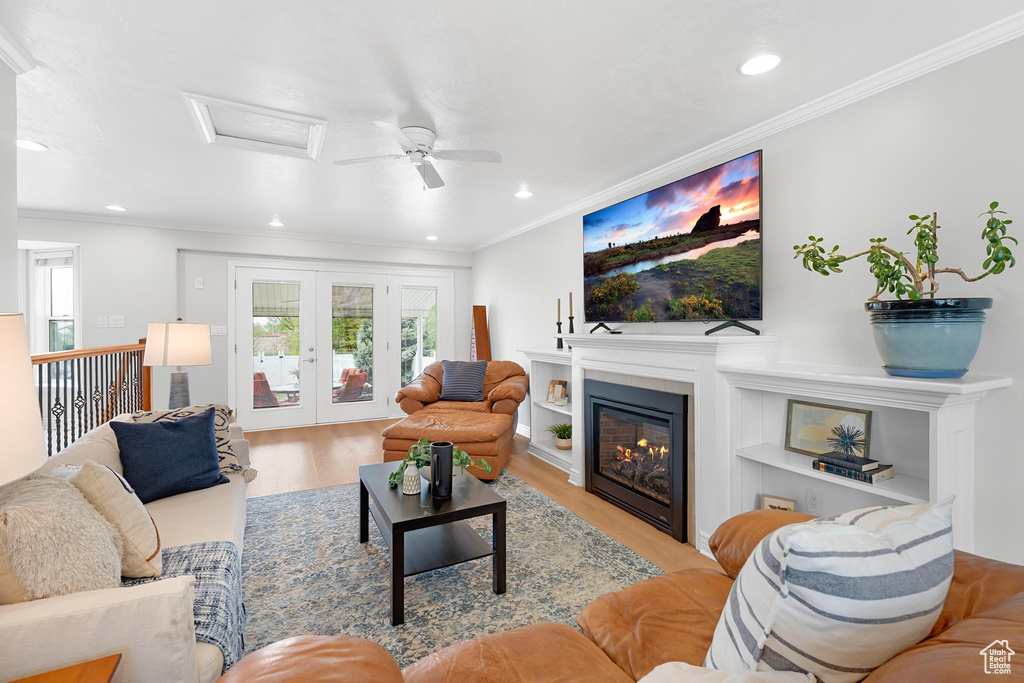 Living room with wood finished floors, attic access, a glass covered fireplace, crown molding, and recessed lighting