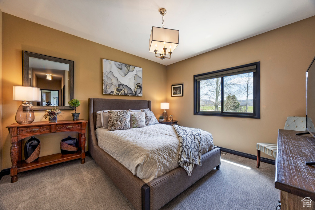 Carpeted bedroom featuring a chandelier and baseboards
