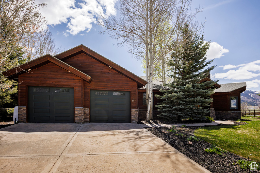 View of front of home featuring stone siding, a garage, and concrete driveway