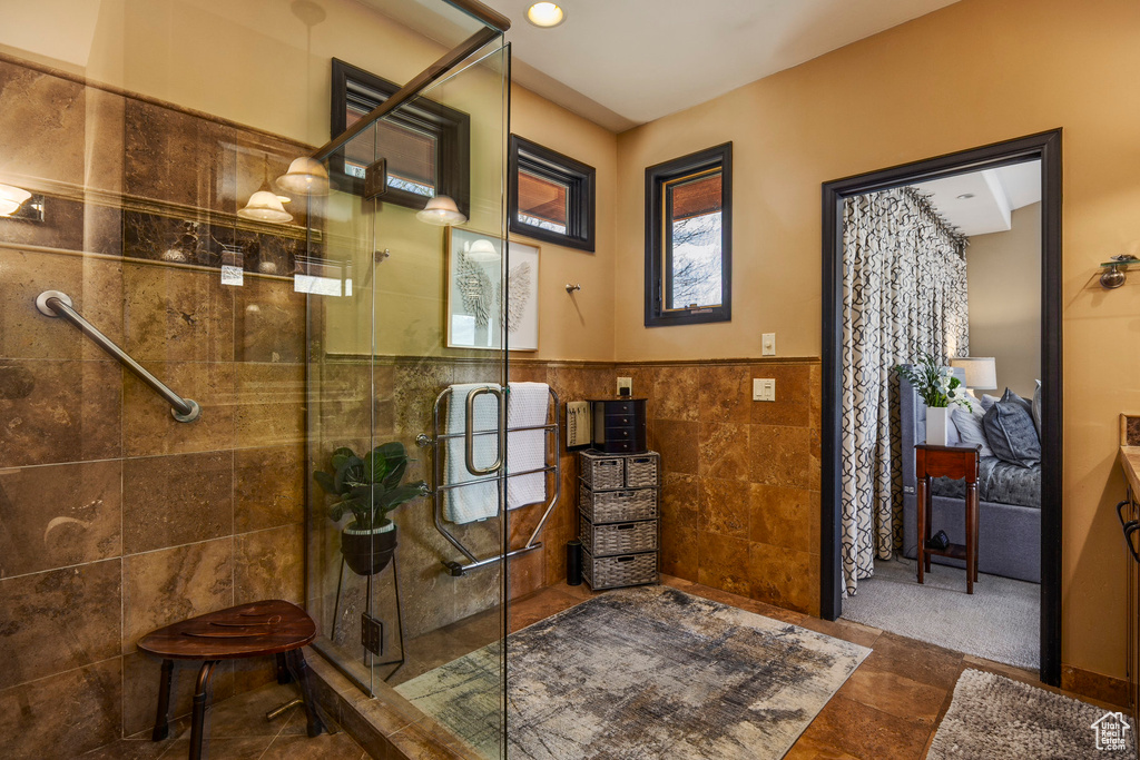 Bathroom featuring tile walls, a stall shower, wainscoting, and tile patterned flooring