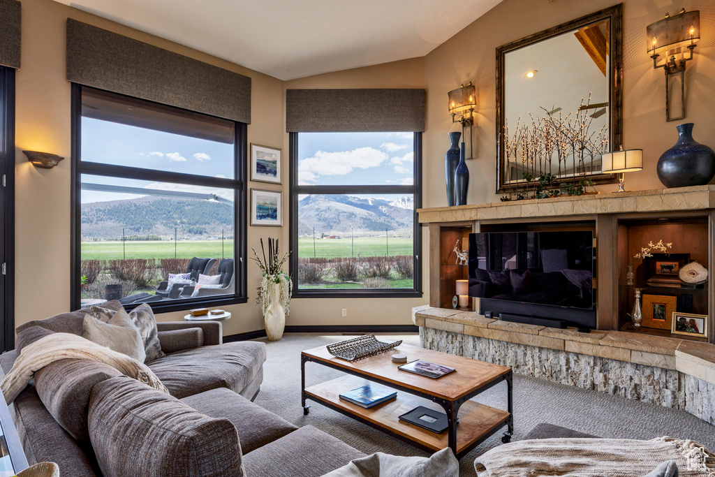 Living area with carpet floors, lofted ceiling, plenty of natural light, and baseboards