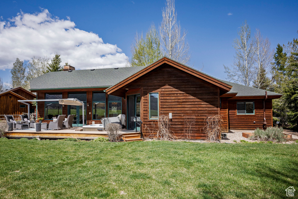 Back of property featuring outdoor lounge area, a deck, a lawn, and roof with shingles