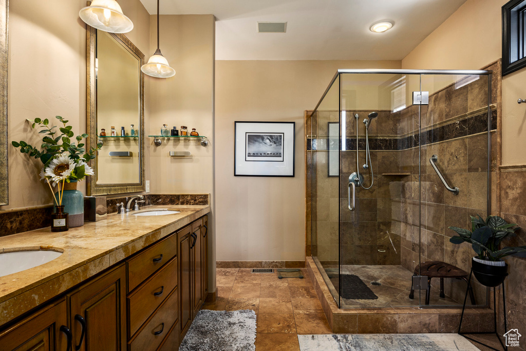 Bathroom featuring a stall shower, double vanity, and baseboards