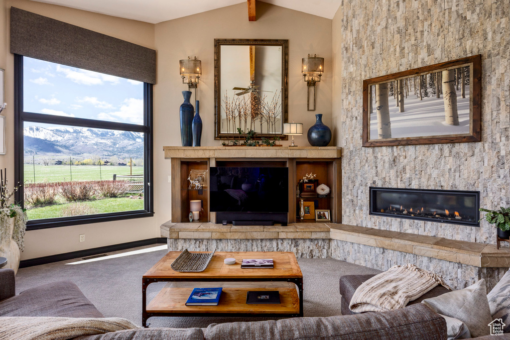 Carpeted living room with lofted ceiling, baseboards, and a glass covered fireplace