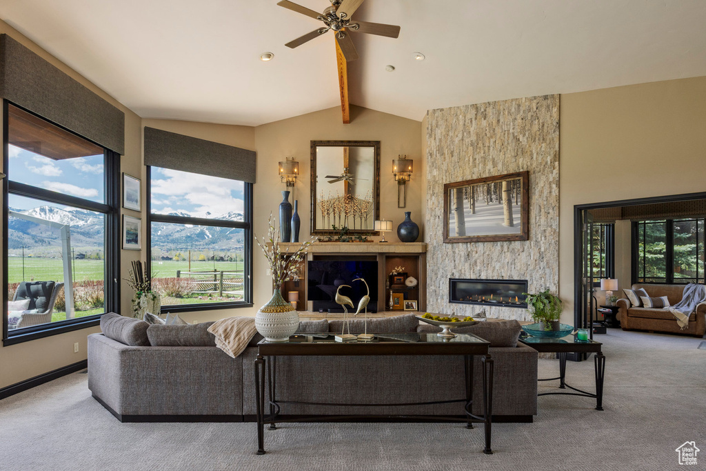 Living room with a stone fireplace, carpet flooring, and healthy amount of natural light
