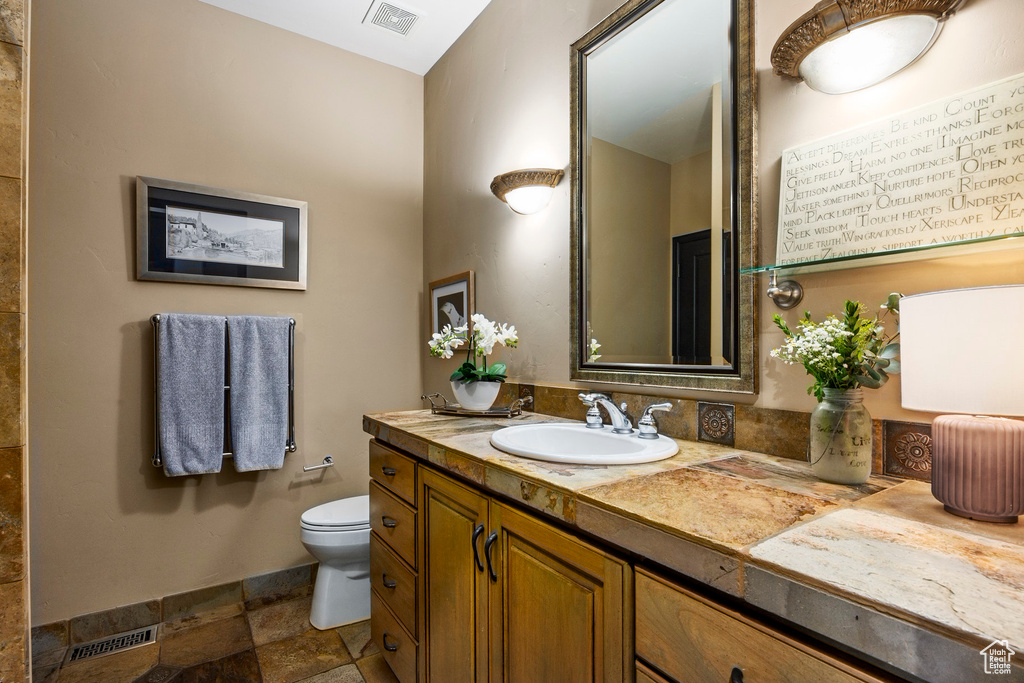 Bathroom with stone tile flooring, toilet, and vanity