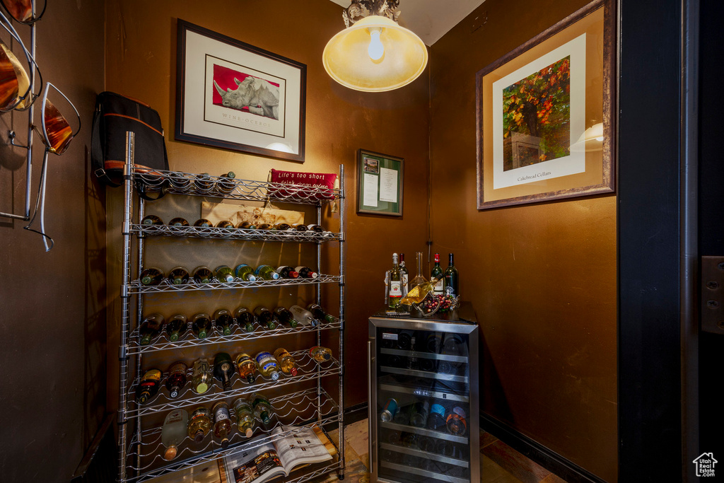 Wine cellar with wine cooler, a bar, and baseboards