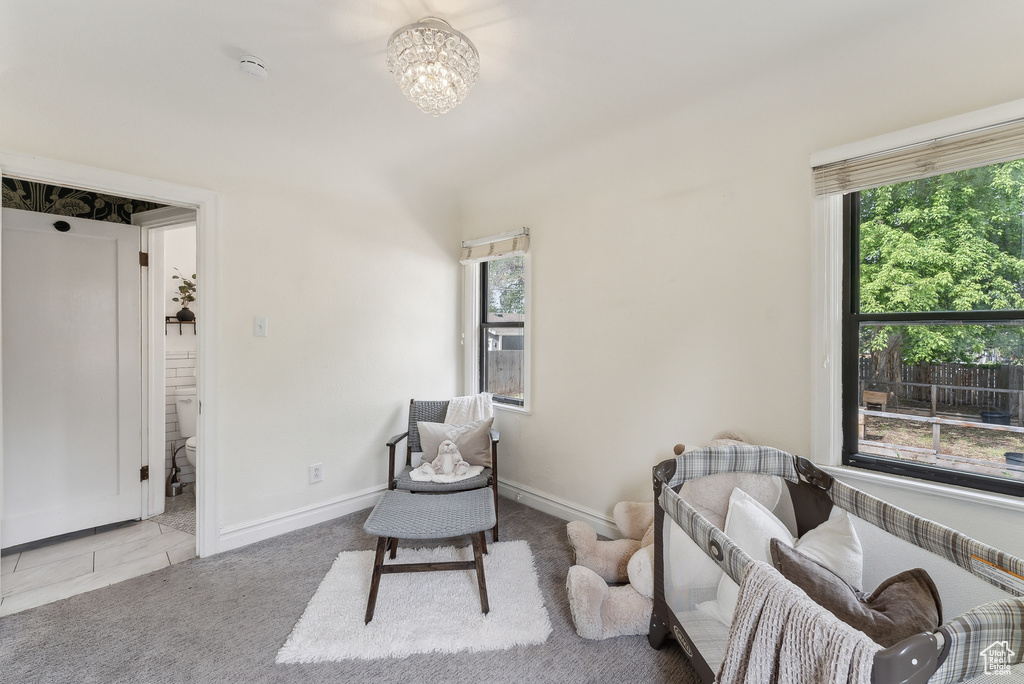Living area with baseboards, a wealth of natural light, a notable chandelier, and carpet floors