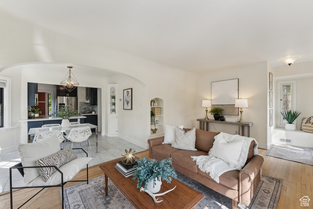 Living room featuring an inviting chandelier, visible vents, baseboards, and arched walkways