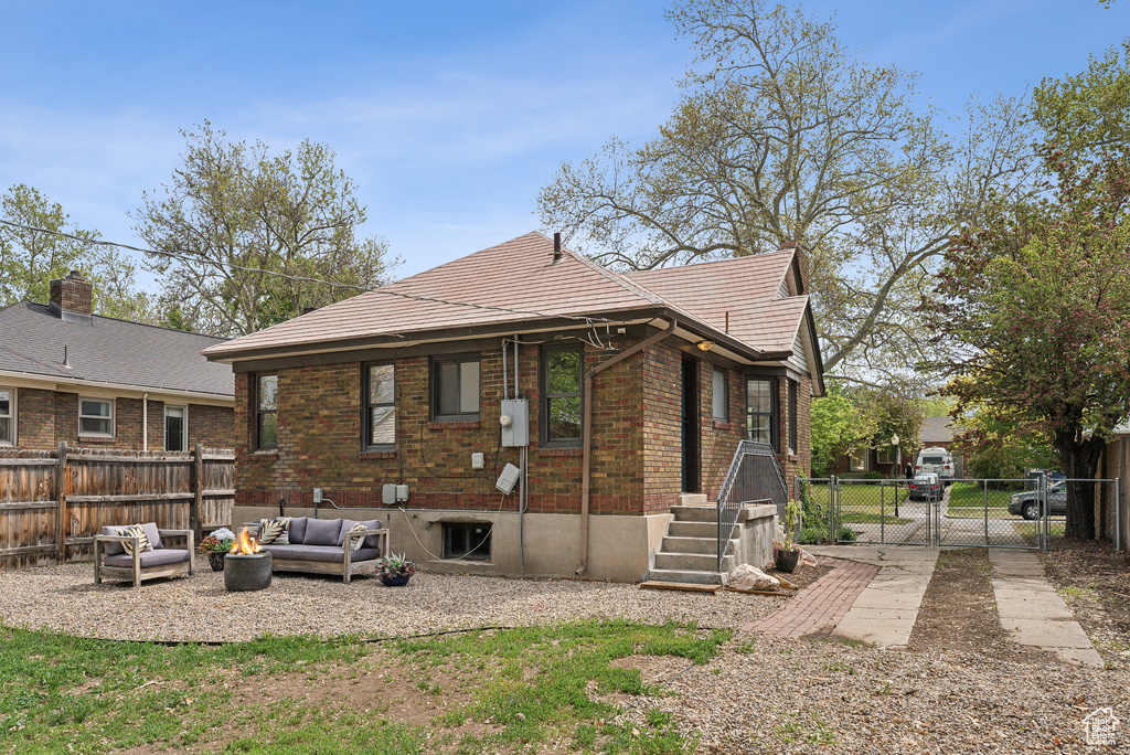 Rear view of property featuring an outdoor hangout area, brick siding, a fenced backyard, and a gate