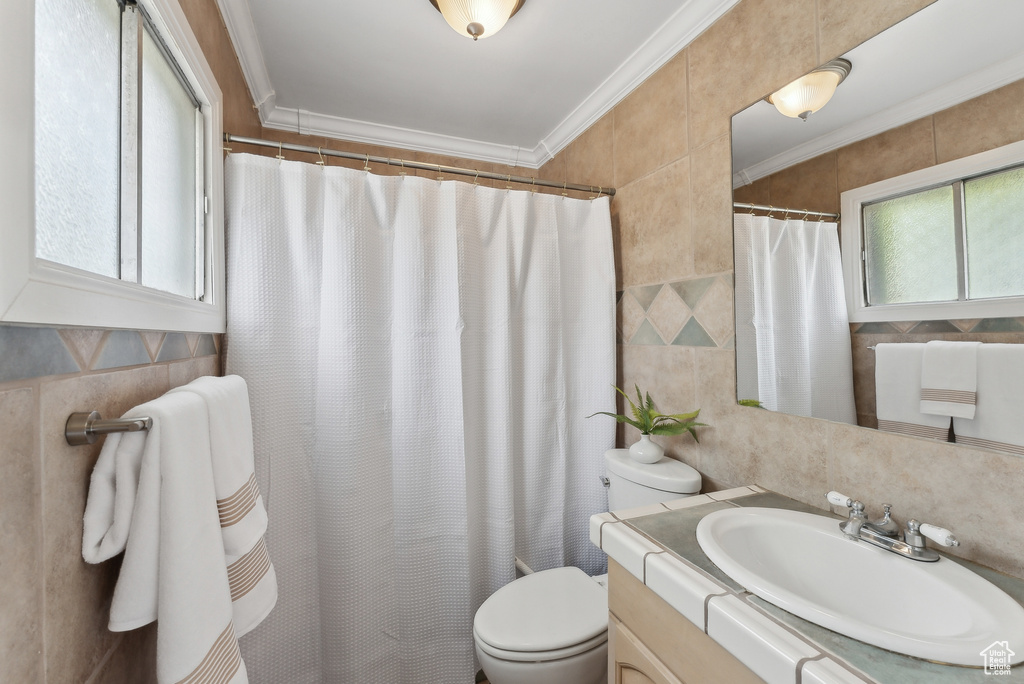 Bathroom featuring tile walls, toilet, a shower with shower curtain, vanity, and crown molding