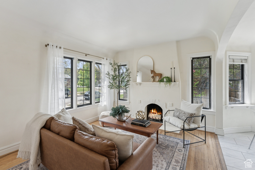 Living room featuring baseboards, light wood-style floors, and a lit fireplace