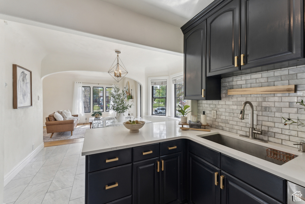 Kitchen with a sink, a peninsula, tasteful backsplash, arched walkways, and light countertops