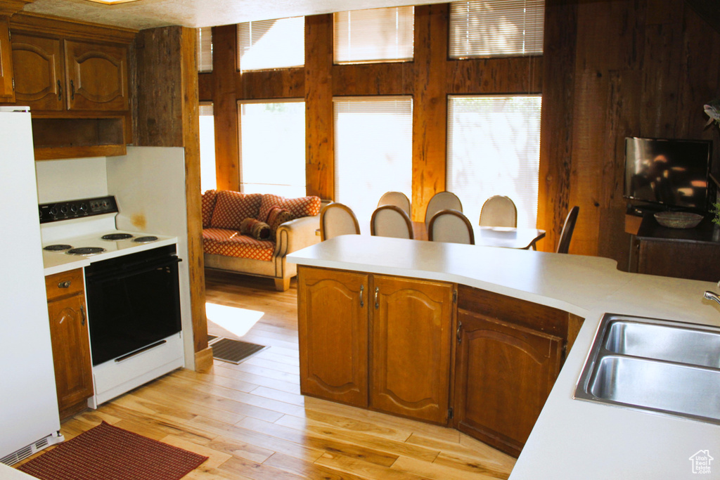 Kitchen with white appliances, light countertops, a sink, and light wood-style flooring