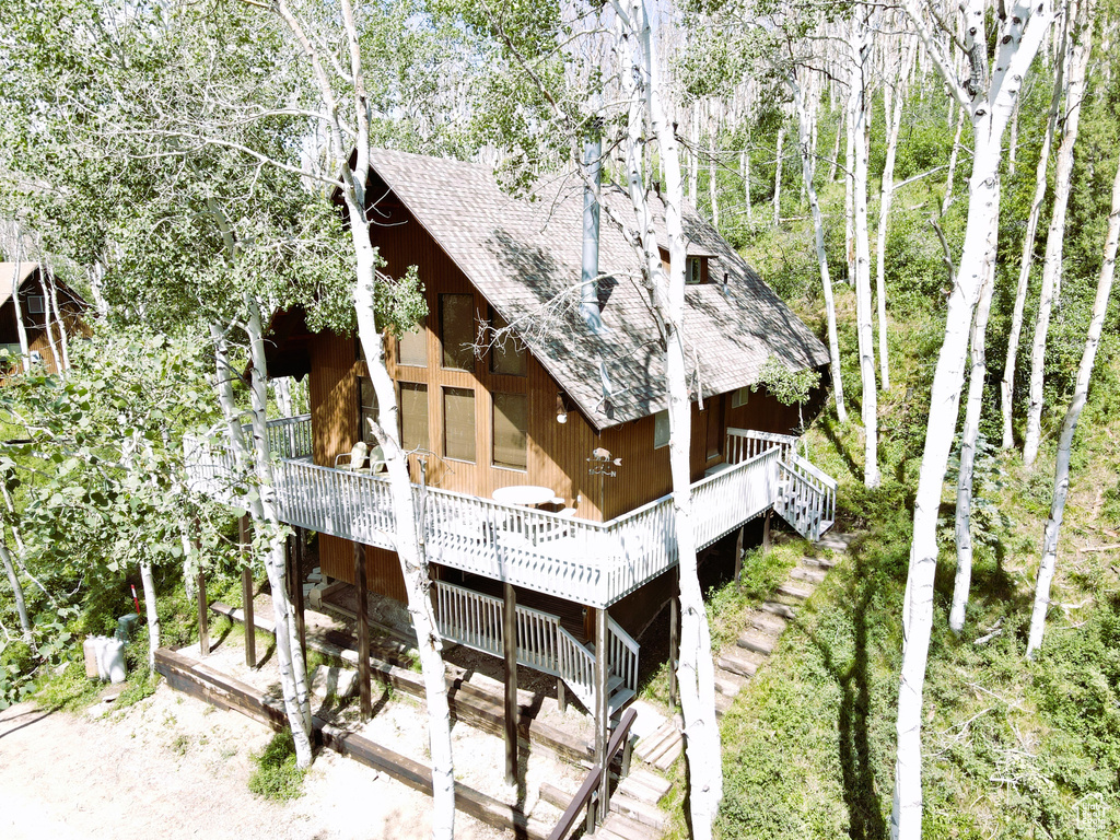 Back of property with a shingled roof, a deck, and stairs
