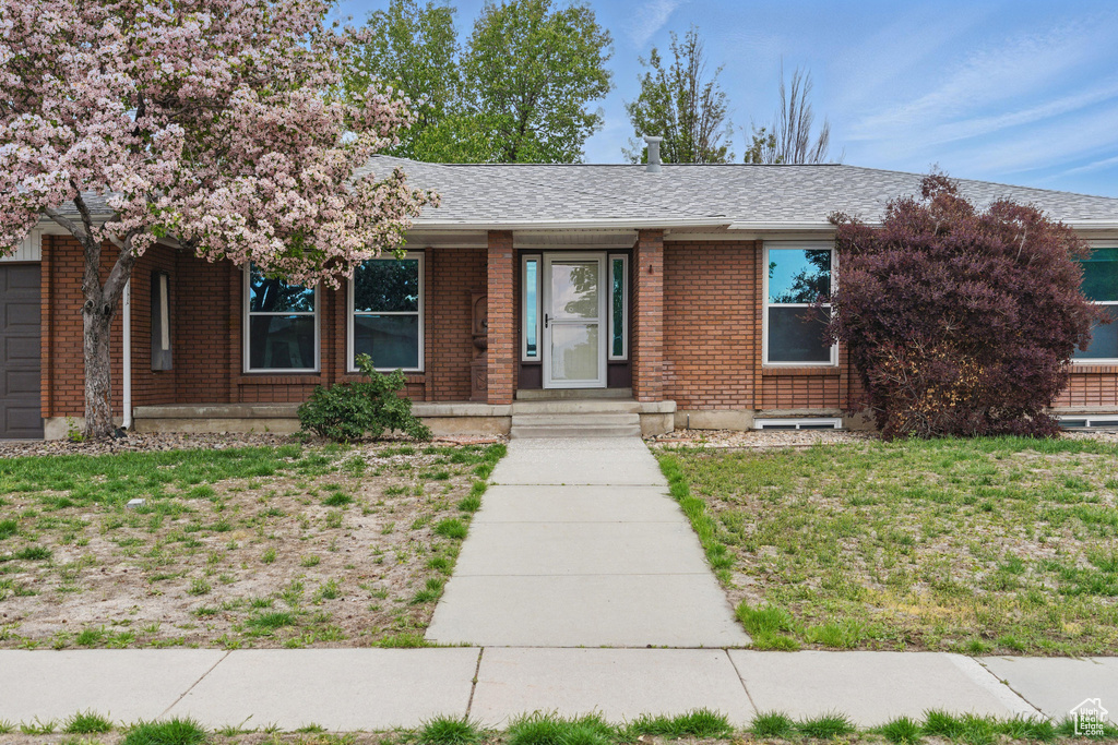 Ranch-style home with brick siding, a shingled roof, and a front yard